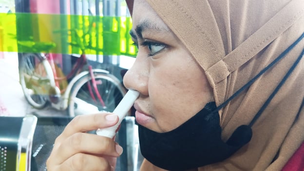 Semarang, Indonesia - March, 2024 - Asian woman using nasal stick inhaler photo