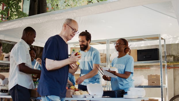 In this shot we see the poor and homeless people receiving free food and nourishments from the hunger relief team of volunteers. Charity workers donating fruits and meals to the underprivileged. photo