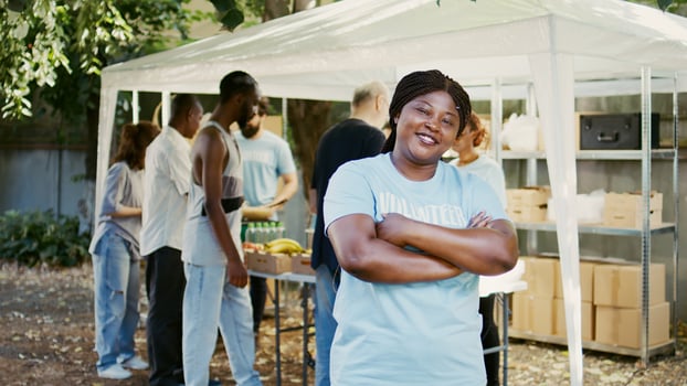 African American female volunteer grins and poses during a food drive charitable event. Humanitarian aid program that provides hunger relief and help to the homeless and the poor. Portrait shot. photo