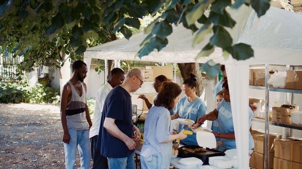 Volunteers serving free food to the needy at an outdoor event. This non-profit organization offers humanitarian aid and fosters community, helping the hungry and homeless. Aerial, handheld. photo