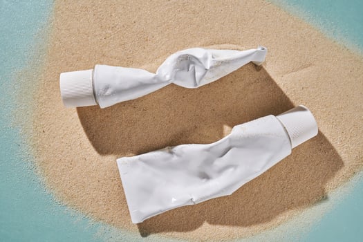 Two tubes of cream on the sand. photo