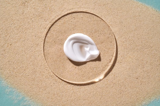 A smear of white sunscreen with SPF against a background of sand. photo