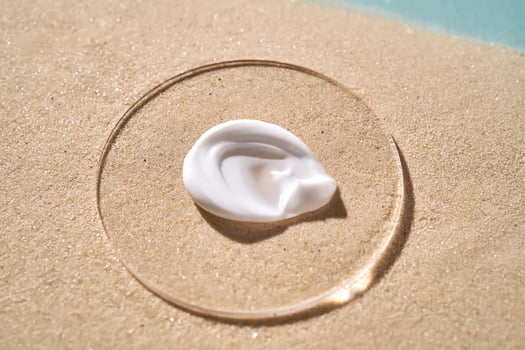 A smear of white sunscreen with SPF against a background of sand. photo