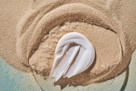 A smear of white sunscreen with SPF against a background of sand. photo