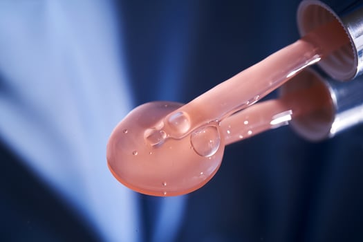 Bottle with pink serum on a blue background. photo