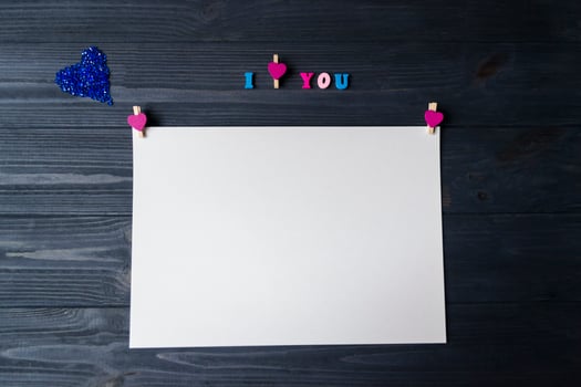 White paper, colorful pencils and decor on a blue wooden background. Greeting card photo