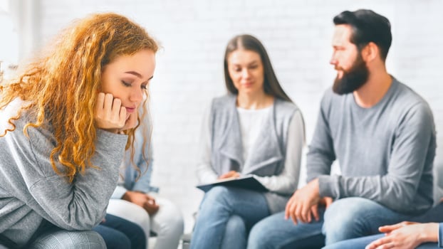 Upset redhead woman sitting at group therapy session photo