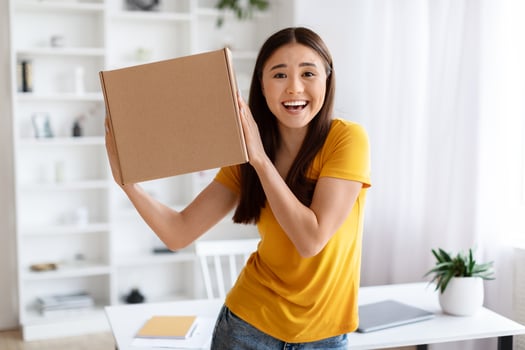 Ecstatic asian woman holding up cardboard box with joyful expression photo