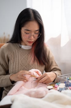 A beautiful Asian woman is focusing on hand-sewing a pattern on cloth on an embroidery frame. photo