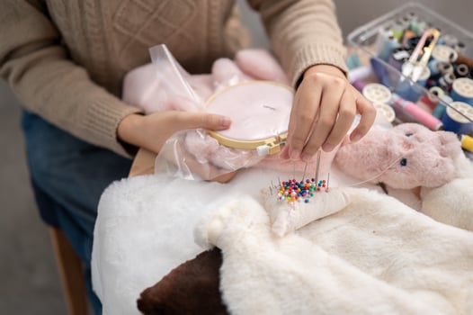 A close-up image of a woman pinning a pin on a pin cushion, stitching cloth, crafting handmade items. photo