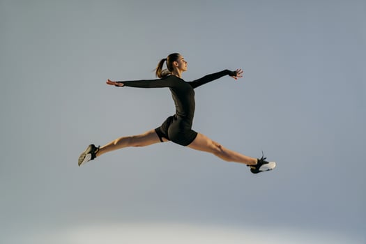 Sporty girl jumping doing split leap in air with joyful expression. Flexible and weightless concept photo