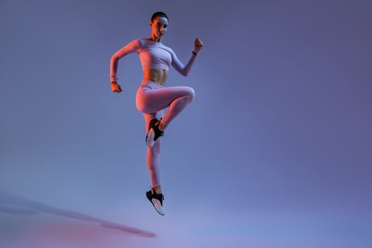 Sporty woman in sportswear jumping on studio background. Sport and healthy lifestyle photo