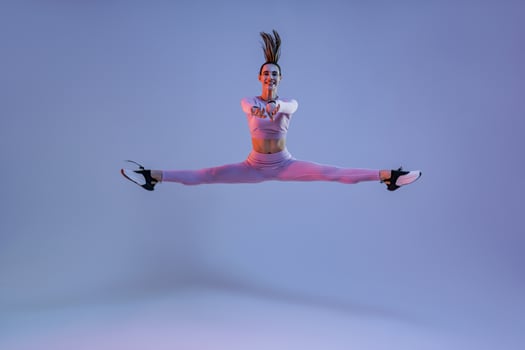 Sporty girl jumping doing split leap in air with joyful expression. Flexible and weightless concept photo