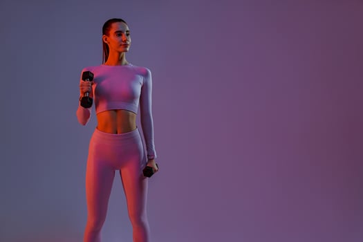 Attractive fitness woman doing exercises with dumbbells on studio background and looking at side photo