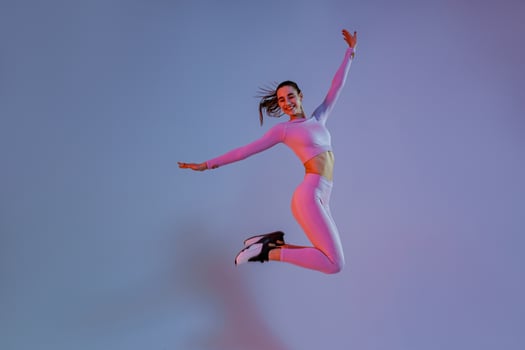Smiling sporty woman in sportswear jumping on studio background. Sport and healthy lifestyle photo