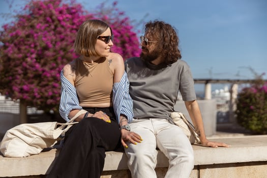 Smiling tourist couple sitting outside on old city street and looking each other photo