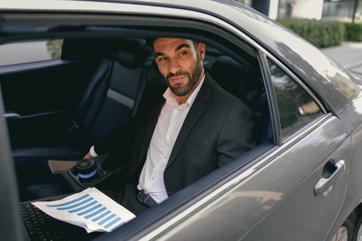 Confidence businessman sitting on car backseat and working with documents and use laptop photo