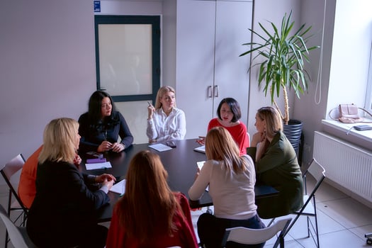 a team of 8 women including a person with a disability in a meeting in the office, top view photo