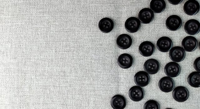 Black sewing buttons on white fabric background. Flat lay, top view. photo