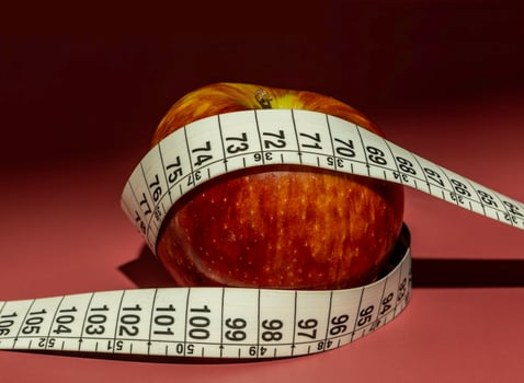 Tape measure and apple symbolizing diet and obesity photo