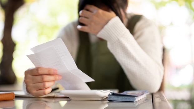 A stressed Asian female small business owner is calculating bills, worried about her shop expenses. photo