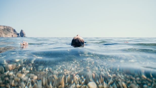 Woman swimming in sea at sunset, float on calm water back view. Concept of body image and fitness, enjoying a serene beach. Happy woman with perfect fit body enjoys sea beach photo