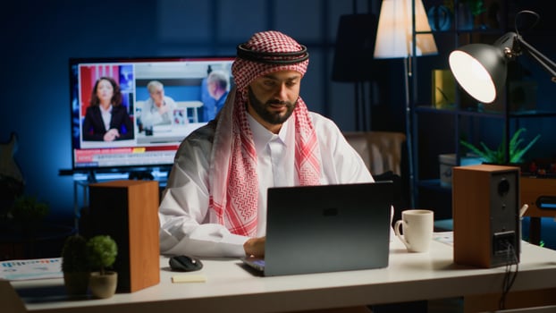 Arab businessman starting his day working from home, opening laptop, surfing the net. Middle Eastern man arriving in personal apartment office with cup of coffee, ready to solve tasks photo