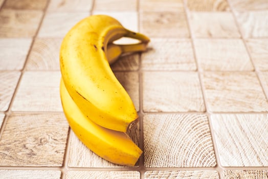 Two ripe yellow bananas in a ring on a checkered wooden surface photo