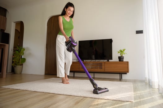 Young happy woman using a vacuum cleaner the floor in living room photo
