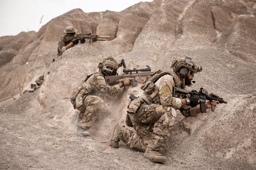 Soldiers in camouflage uniforms aiming with their riflesready to fire during military operation in the desert soldiers training  in a military operation photo