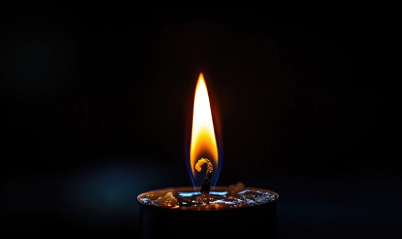 Close-up of a candlewick glowing brightly amidst the darkness photo