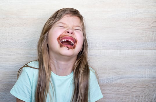 Happy and laughing little girl eating chocolate dirty face. Close up of kid with dirty face in chocolate . photo