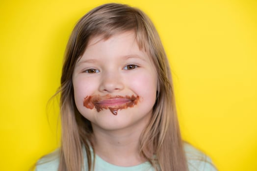 Happy and laughing little girl eating chocolate dirty face. Close up of kid with dirty face in chocolate . photo