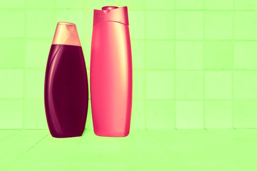 Brown red plastic bottles for detergents and shampoos on a checker green background photo