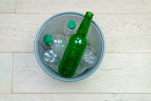 Six different plastic and glass bottles in the office trash can. Ecology and recycling of waste from various raw materials photo