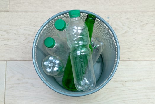 Six different plastic and glass bottles in the office trash can. Ecology and recycling of waste from various raw materials photo