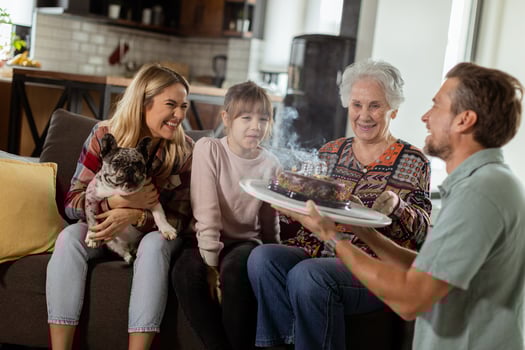 Joyous Family Celebrating Grandmothers Birthday With Cake in a Cozy Living Room photo