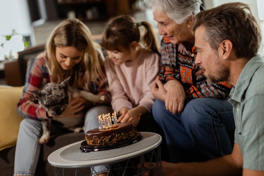 Joyous Family Celebrating Grandmothers Birthday With Cake in a Cozy Living Room photo