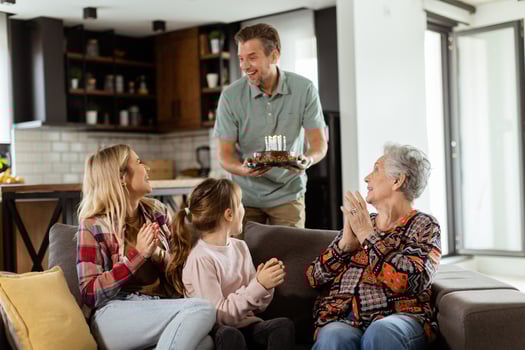 Joyous Family Celebrating Grandmothers Birthday With Cake in a Cozy Living Room photo
