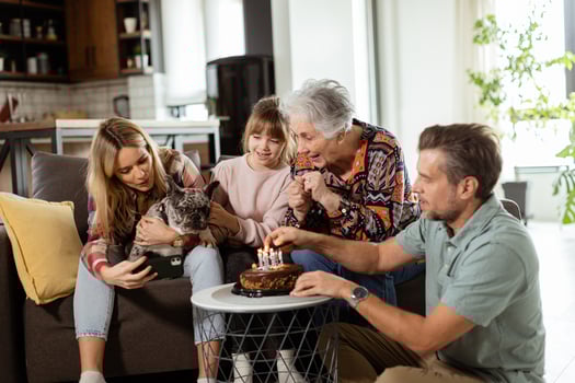 Joyous Family Celebrating Grandmothers Birthday With Cake in a Cozy Living Room photo