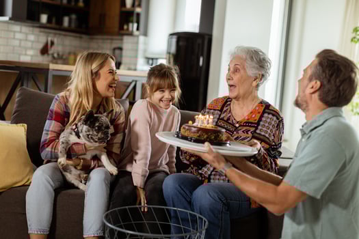 Joyous Family Celebrating Grandmothers Birthday With Cake in a Cozy Living Room photo