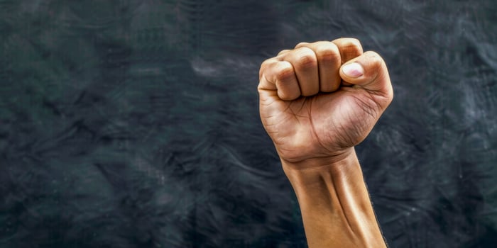 AI generated A strong and powerful image of a person raising their fist in the air, symbolizing defiance and protest. The gesture exudes empowerment and determination photo