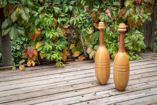 pair of wooden Indian exercise clubs on a wooden rustic deck, fall scenery photo