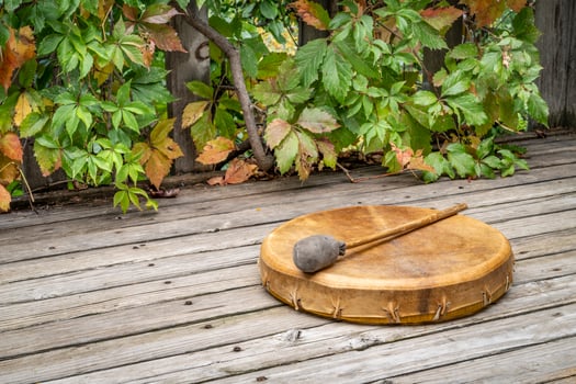 handmade, native American style, shaman frame drum covered by goat skin with a beater on a rustic wooden backyard deck photo