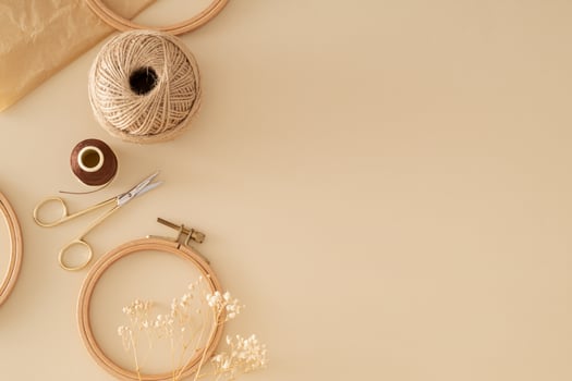 Creative vintage composition of sewing scissors, thread, jute, embroidery hoop, dry flowers and old crumpled paper on beige background with copy space. Minimal handmade sewing accessories concept. photo