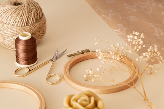 Creative vintage composition of sewing scissors, thread, jute, embroidery hoop, dry flowers, gift paper and candle on beige background. Minimal handmade sewing accessories concept. photo