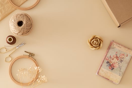 Sewing scissors, thread, jute, embroidery hoop, dry flowers, paper gift box, candle, old crumpled paper and vintage notebook on beige background. Creative minimal handmade accessories concept. photo