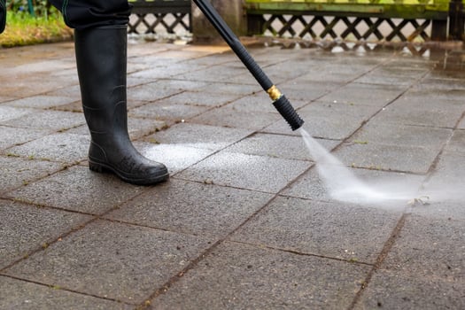 person is using a pressure washer to clean a brick patio photo