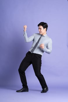 Portrait of Asian male businessman standing and posing on purple background photo