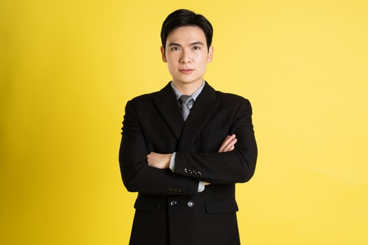 Portrait of Asian male businessman. wearing a suit and posing on a yellow background photo